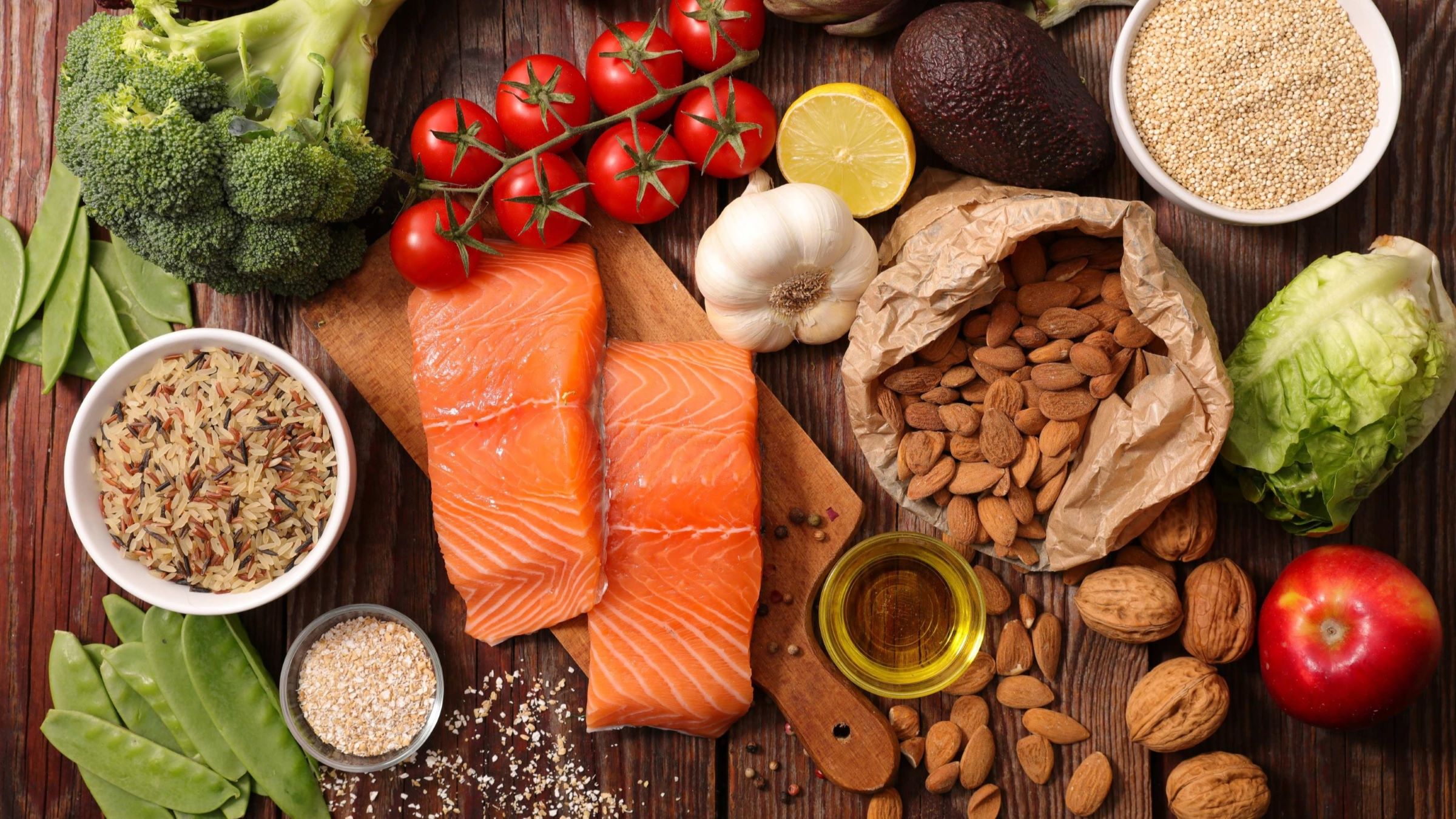 Image of a table with fresh fruits and vegetables, fish, nuts, and grains