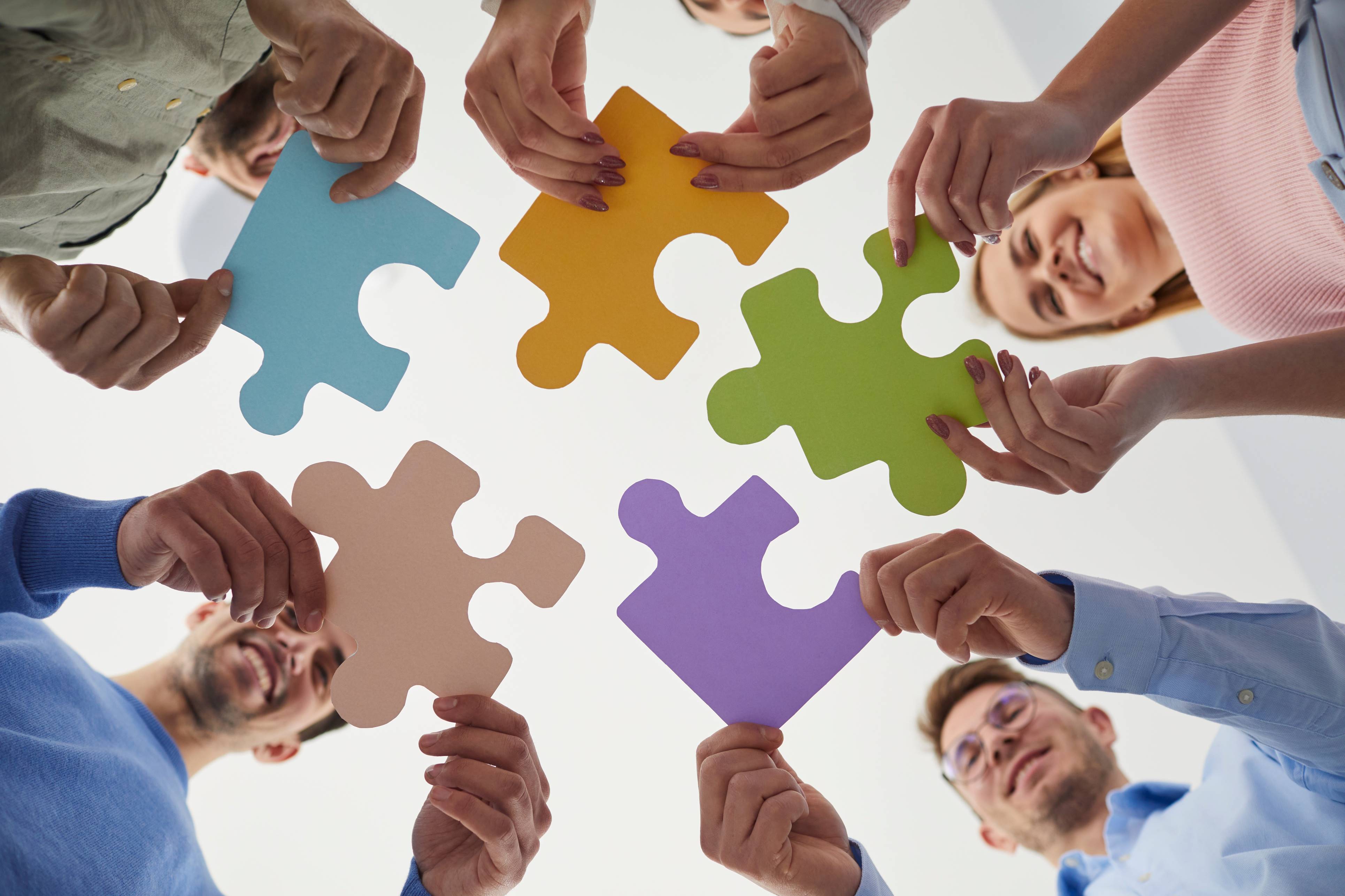 Image of team members holding pieces of a jigsaw puzzle