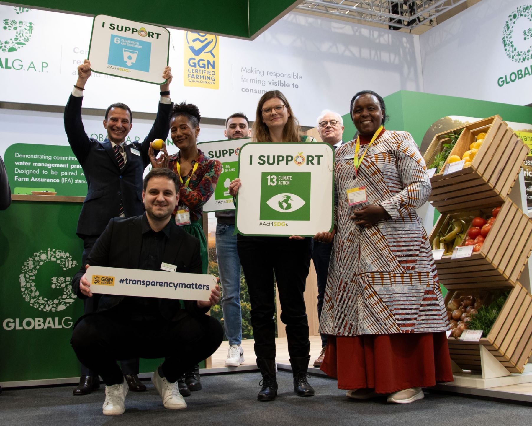 Stakeholders holding signs related to the UN Sustainable Development Goals at the GLOBALG.A.P. booth at Fruit Logistica 2024 in Berlin.